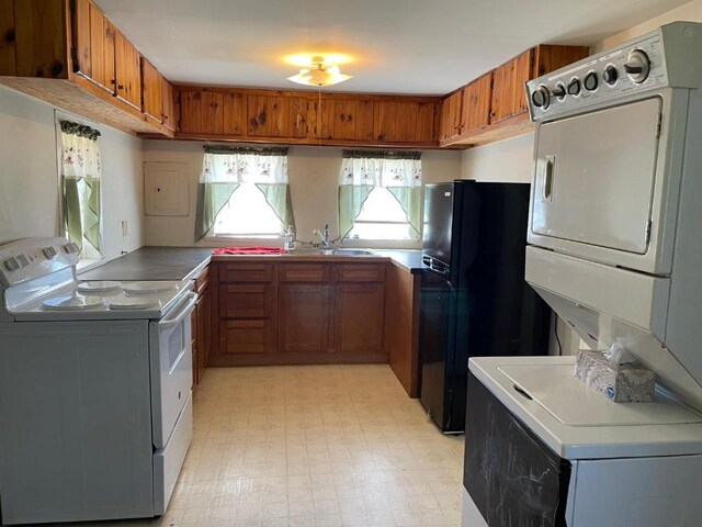 kitchen with light tile floors, electric range, stacked washing maching and dryer, sink, and black refrigerator