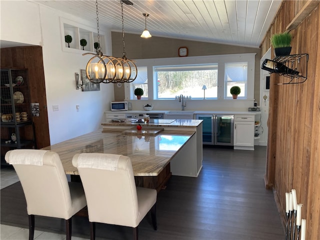 dining area with wood walls, dark hardwood / wood-style floors, wooden ceiling, beverage cooler, and sink