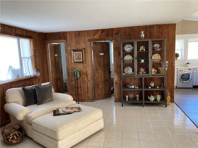 tiled living room featuring washer / dryer, plenty of natural light, and wooden walls