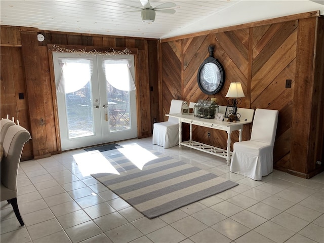 sitting room with ceiling fan, light tile patterned floors, and wooden walls