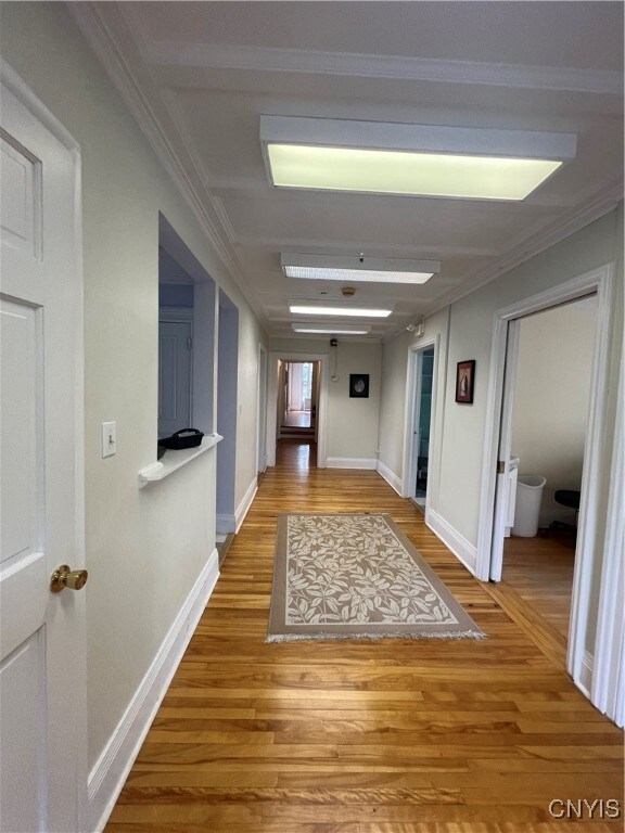 hall with wood-type flooring and crown molding