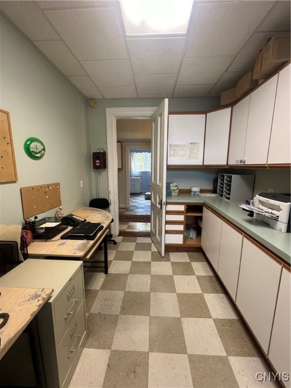 kitchen with white cabinets, a paneled ceiling, and built in desk