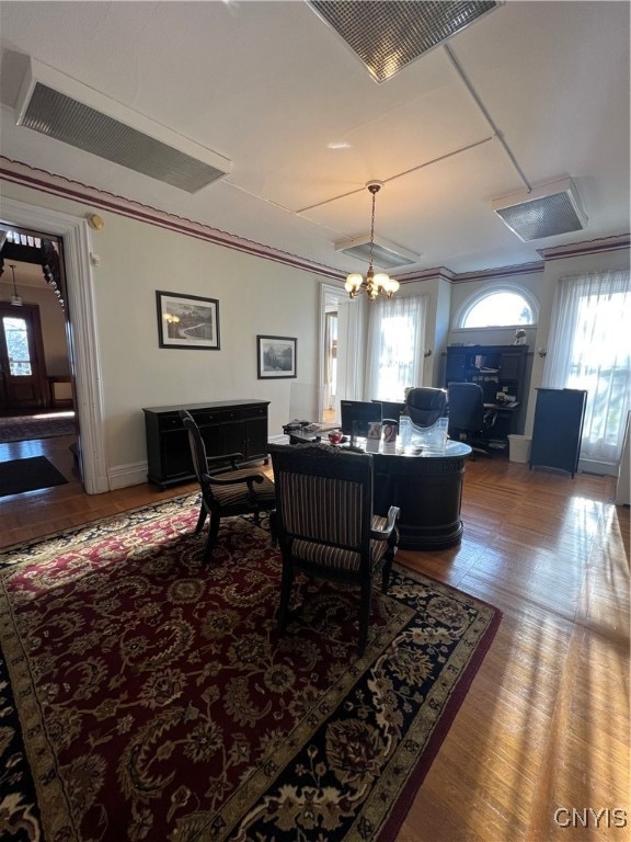 living room featuring an inviting chandelier, hardwood / wood-style flooring, and crown molding