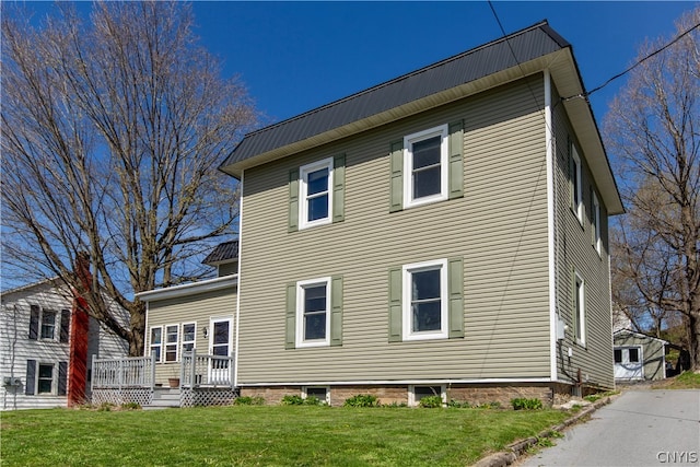 rear view of property featuring a lawn and a wooden deck