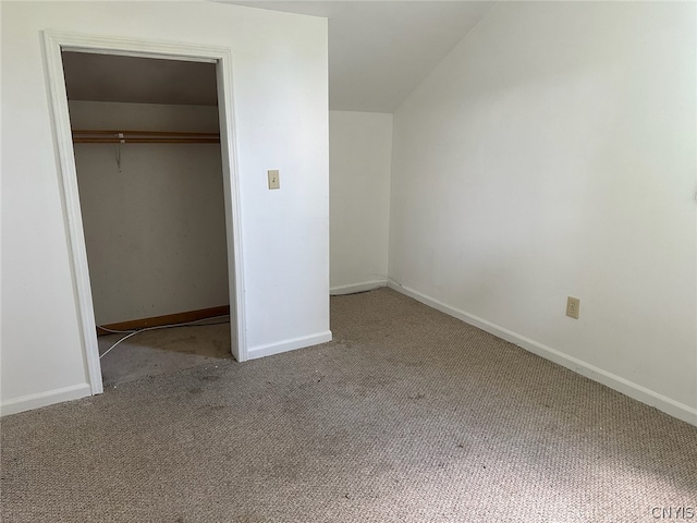 unfurnished bedroom with a closet, lofted ceiling, and carpet flooring