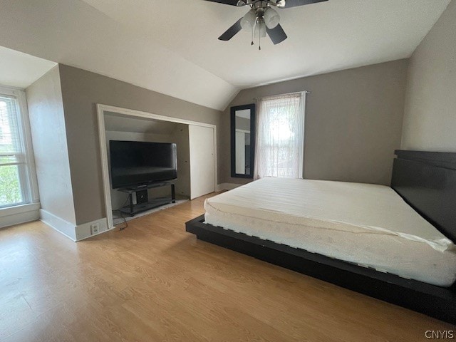 bedroom featuring wood-type flooring, lofted ceiling, ceiling fan, and a closet