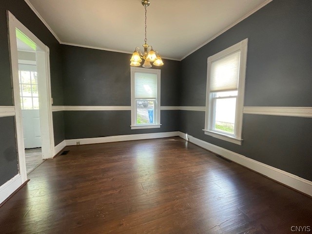 spare room with dark hardwood / wood-style flooring, crown molding, and a notable chandelier