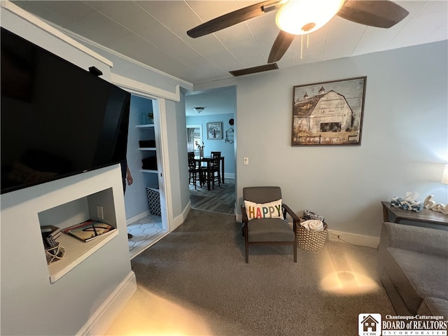 sitting room with carpet floors, ceiling fan, and built in shelves