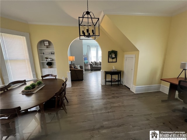 dining room with dark hardwood / wood-style floors, a notable chandelier, built in shelves, and ornamental molding