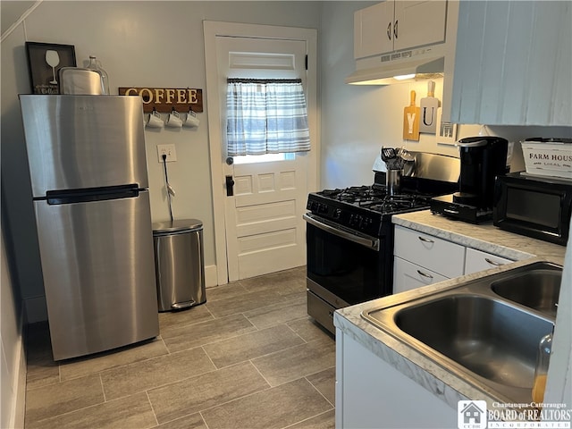 kitchen featuring appliances with stainless steel finishes, sink, light tile flooring, and white cabinets