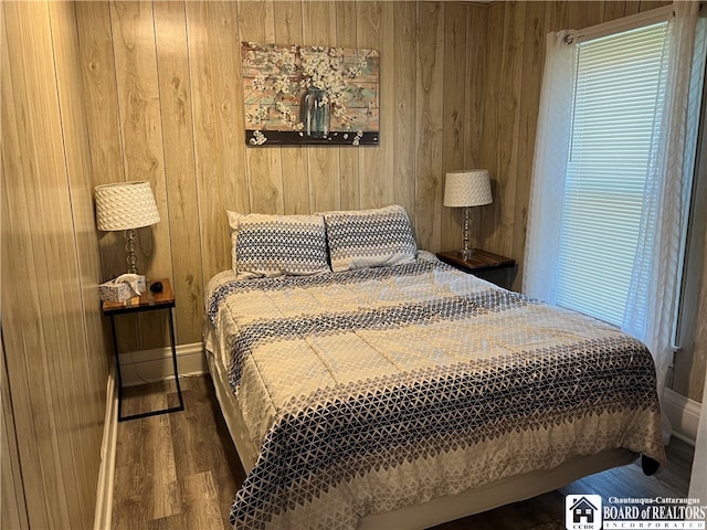 bedroom featuring wooden walls and dark hardwood / wood-style floors