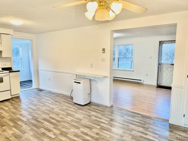 kitchen with white electric range oven, white cabinetry, light hardwood / wood-style flooring, and a baseboard heating unit