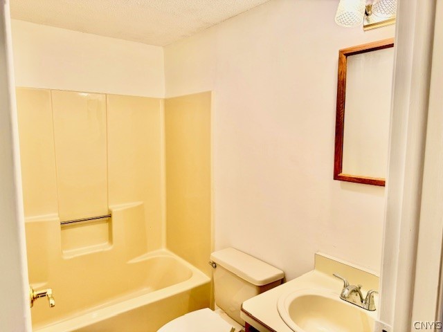 full bathroom with shower / tub combination, vanity, toilet, and a textured ceiling