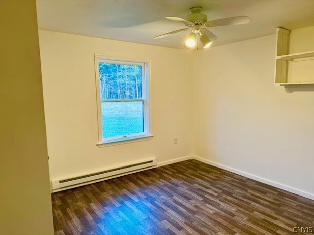 spare room with ceiling fan, baseboard heating, and dark hardwood / wood-style flooring