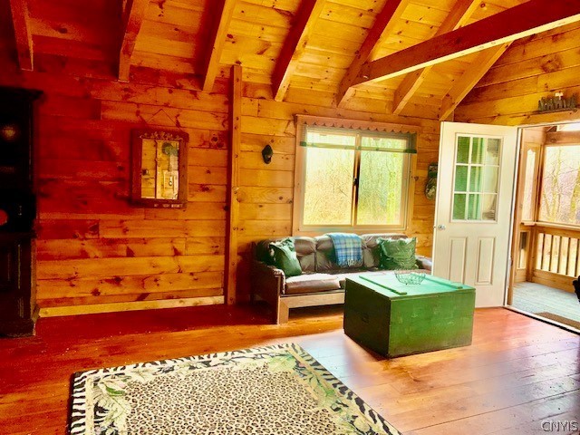 interior space with wood walls, wood-type flooring, vaulted ceiling with beams, and wooden ceiling