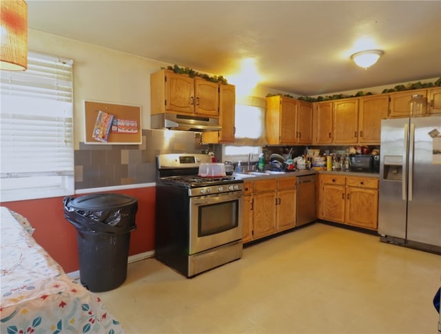 kitchen featuring appliances with stainless steel finishes, sink, backsplash, and light tile floors