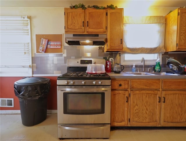 kitchen featuring backsplash, stainless steel gas stove, custom exhaust hood, sink, and light tile floors