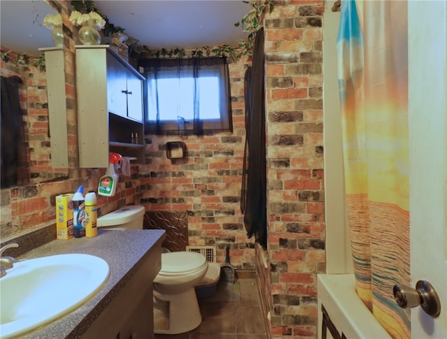 bathroom featuring tile flooring, oversized vanity, toilet, and brick wall