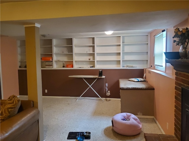 interior space with built in shelves and a brick fireplace