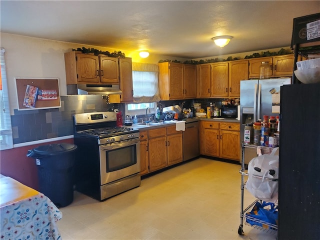 kitchen with appliances with stainless steel finishes, sink, tasteful backsplash, and light tile floors