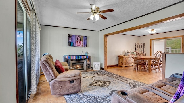 living room with a textured ceiling, parquet floors, ornamental molding, and ceiling fan