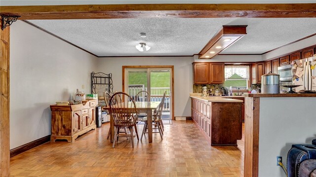 dining area featuring crown molding, a textured ceiling, and light parquet flooring