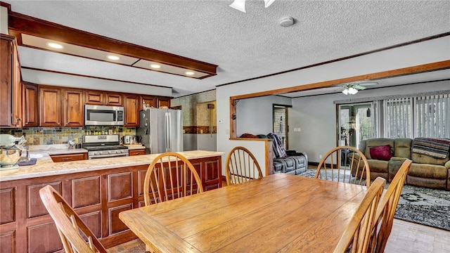 dining area featuring a textured ceiling, ornamental molding, and ceiling fan