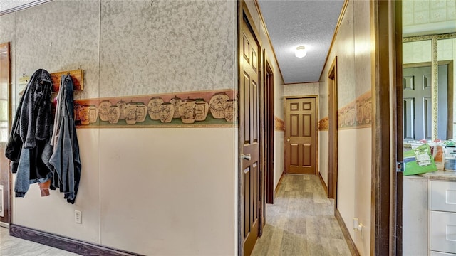 hall with light hardwood / wood-style floors and a textured ceiling