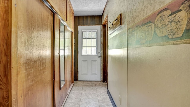 doorway to outside with a textured ceiling and light tile floors