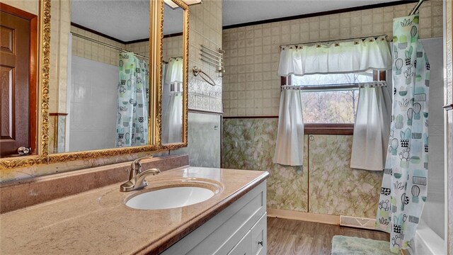 bathroom featuring hardwood / wood-style flooring, shower / bath combination with curtain, ornamental molding, vanity, and a textured ceiling