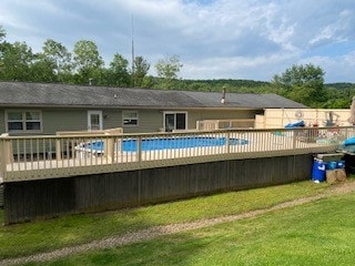 back of house featuring a pool side deck and a yard