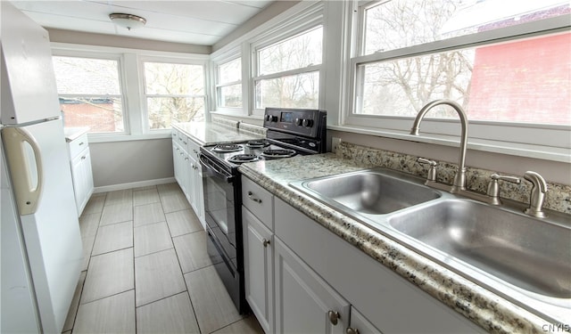 kitchen featuring light tile flooring, white refrigerator, black range with electric cooktop, white cabinetry, and sink