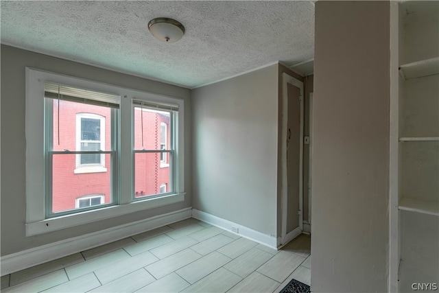 spare room with a textured ceiling and light tile flooring