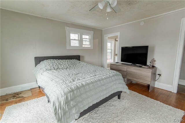 bedroom with a textured ceiling, ceiling fan, and dark wood-type flooring