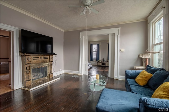 living room featuring crown molding, dark hardwood / wood-style flooring, ceiling fan, and a textured ceiling