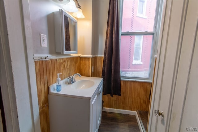 bathroom featuring wooden walls, hardwood / wood-style floors, and large vanity