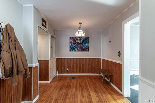 unfurnished dining area featuring crown molding and light wood-type flooring