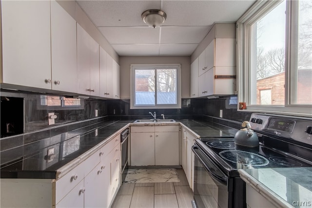 kitchen featuring black electric range, sink, backsplash, and white cabinets