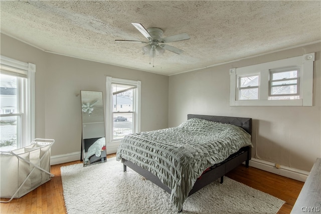 bedroom with hardwood / wood-style floors, multiple windows, and ceiling fan