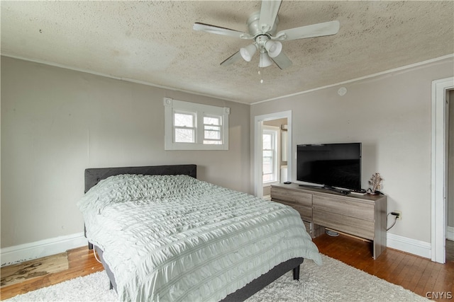 bedroom with hardwood / wood-style floors, ceiling fan, and a textured ceiling