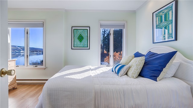 bedroom with crown molding, a water view, a baseboard radiator, and hardwood / wood-style flooring