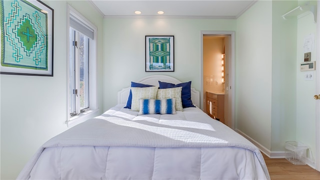 bedroom with connected bathroom, light hardwood / wood-style floors, and ornamental molding