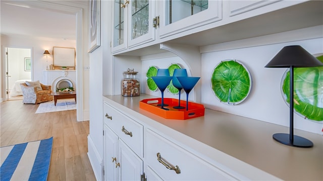 bar with light hardwood / wood-style floors and white cabinetry