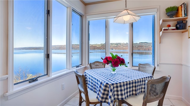 tiled dining area with crown molding and a water view