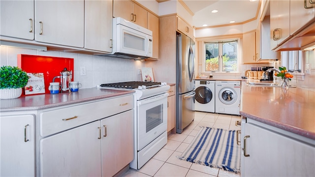 kitchen featuring washer and clothes dryer, white appliances, backsplash, sink, and light tile patterned flooring