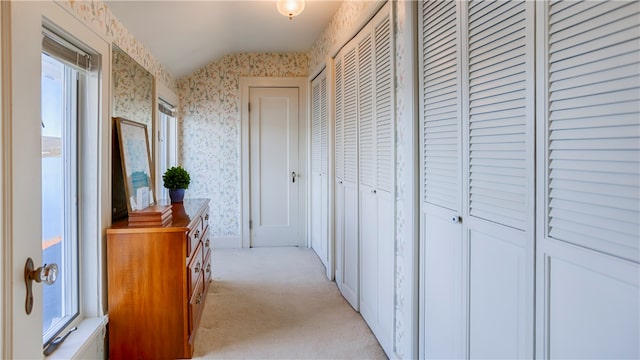 corridor featuring light colored carpet and vaulted ceiling