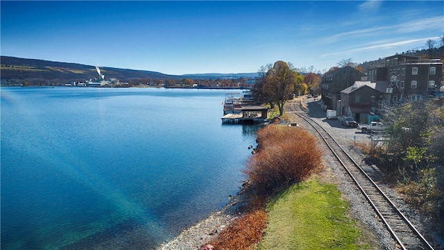 property view of water with a mountain view and a dock