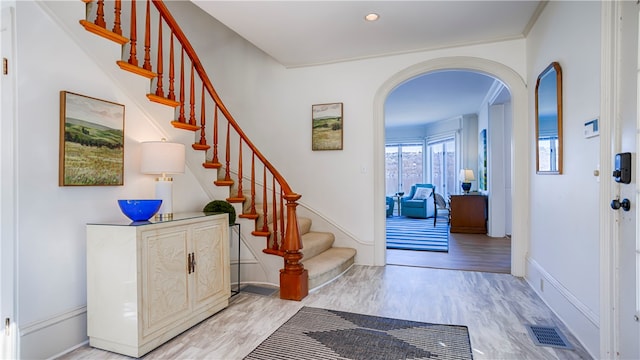 foyer entrance with light hardwood / wood-style floors and crown molding