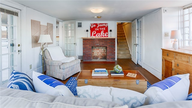 living room featuring plenty of natural light, dark wood-type flooring, and a brick fireplace