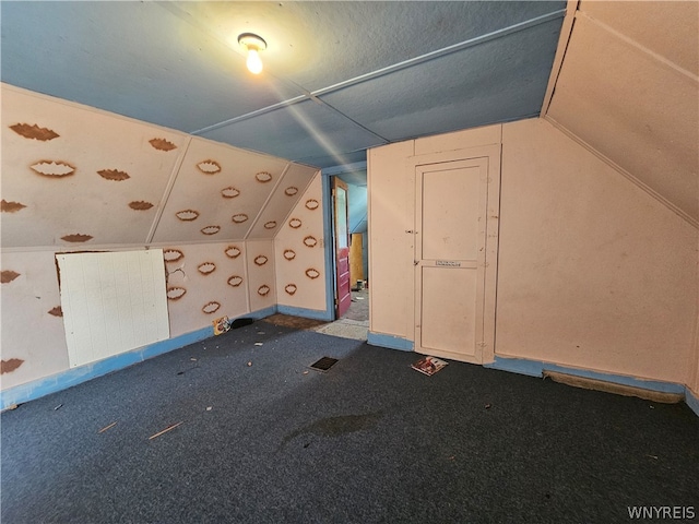 additional living space with dark colored carpet and vaulted ceiling